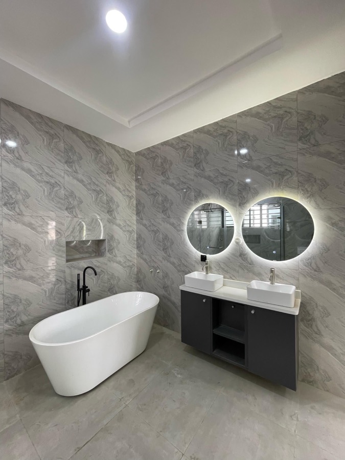 Bathroom with illuminated round mirrors and bathtub